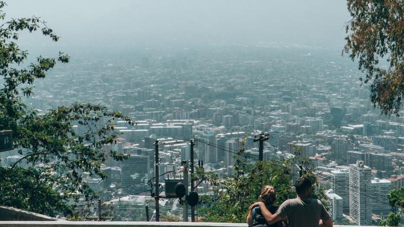 Pareja contemplando la vista panorámica de Santiago desde un mirador de cerro